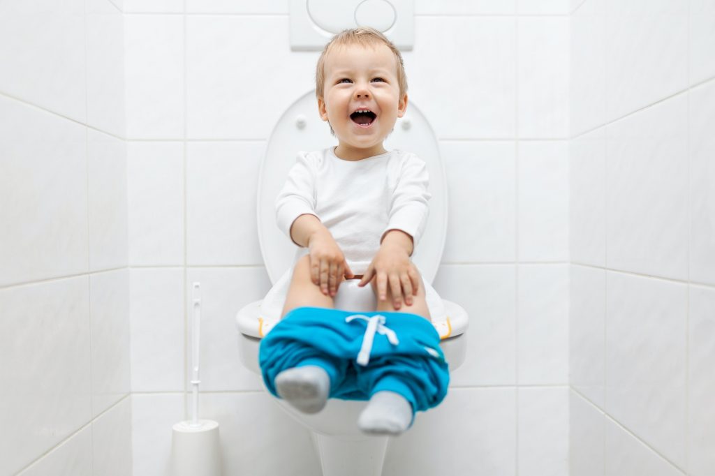 Adorable young child sitting on the toilet