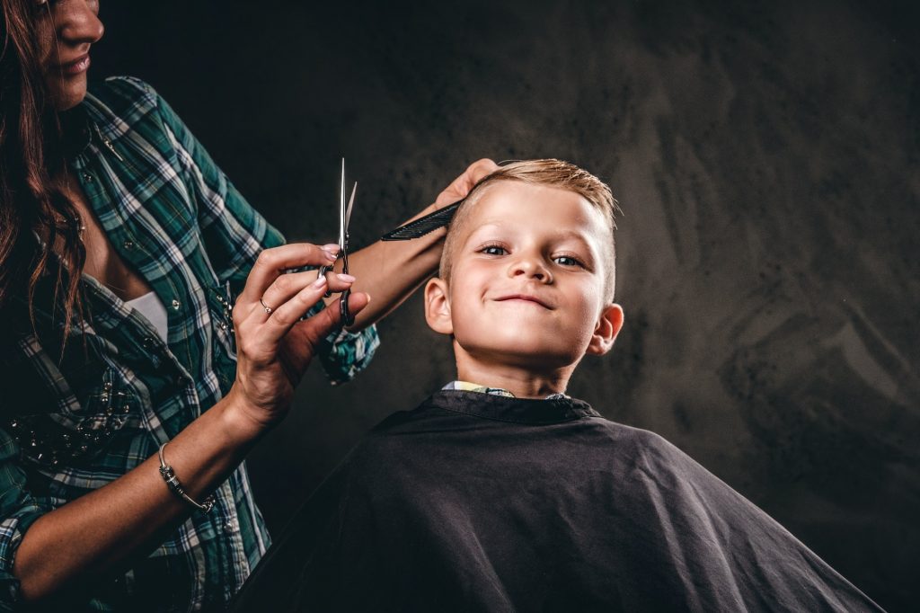 Cute preschool boy getting haircut.