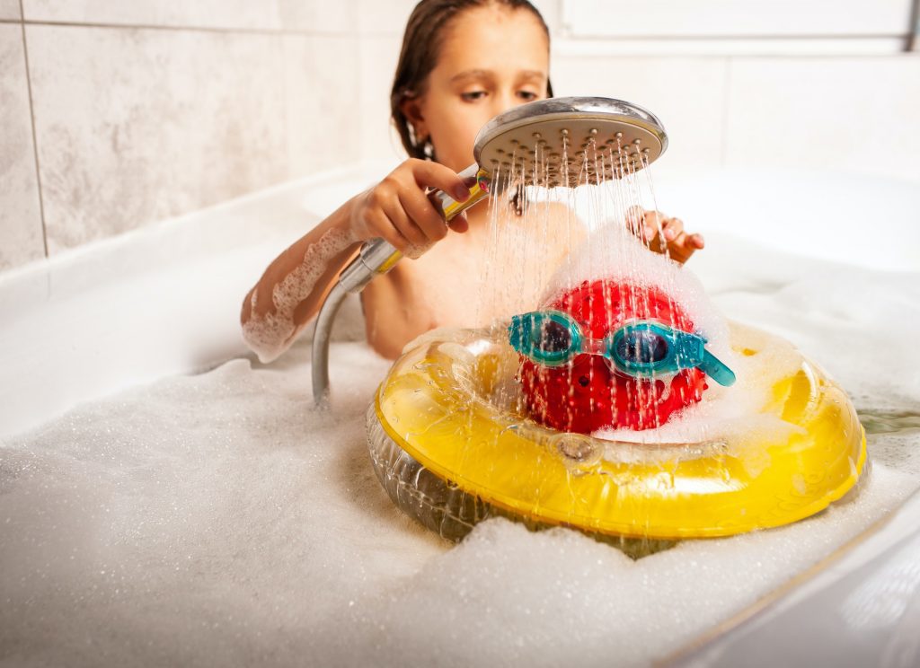 Funny little unidentified girl showering a head made of a ball