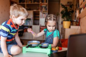 Kids watching food blogger video on the screen of laptop and playing in master chef happy kid, lapt