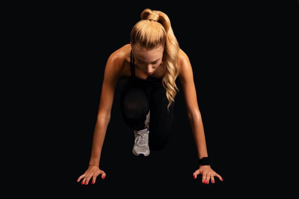 Determined Girl Standing In Ready To Run Position, Black Background