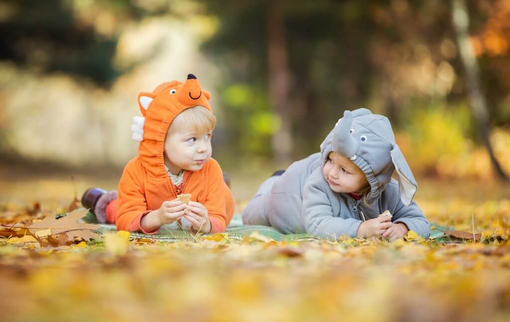 Little children in animal costumes playing in autumn forest
